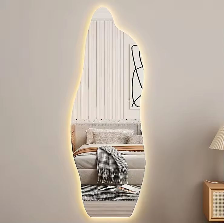 Oval-shaped mirror with LED lighting in a room with a sofa and lamp.