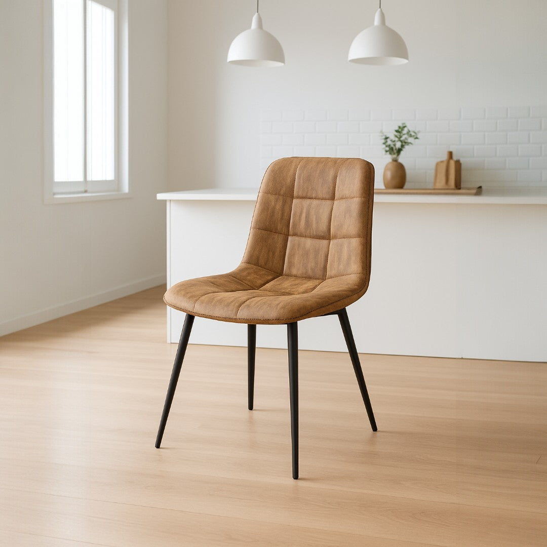 Brown upholstered chair with black legs in a minimalistic room with white walls and wooden floor.