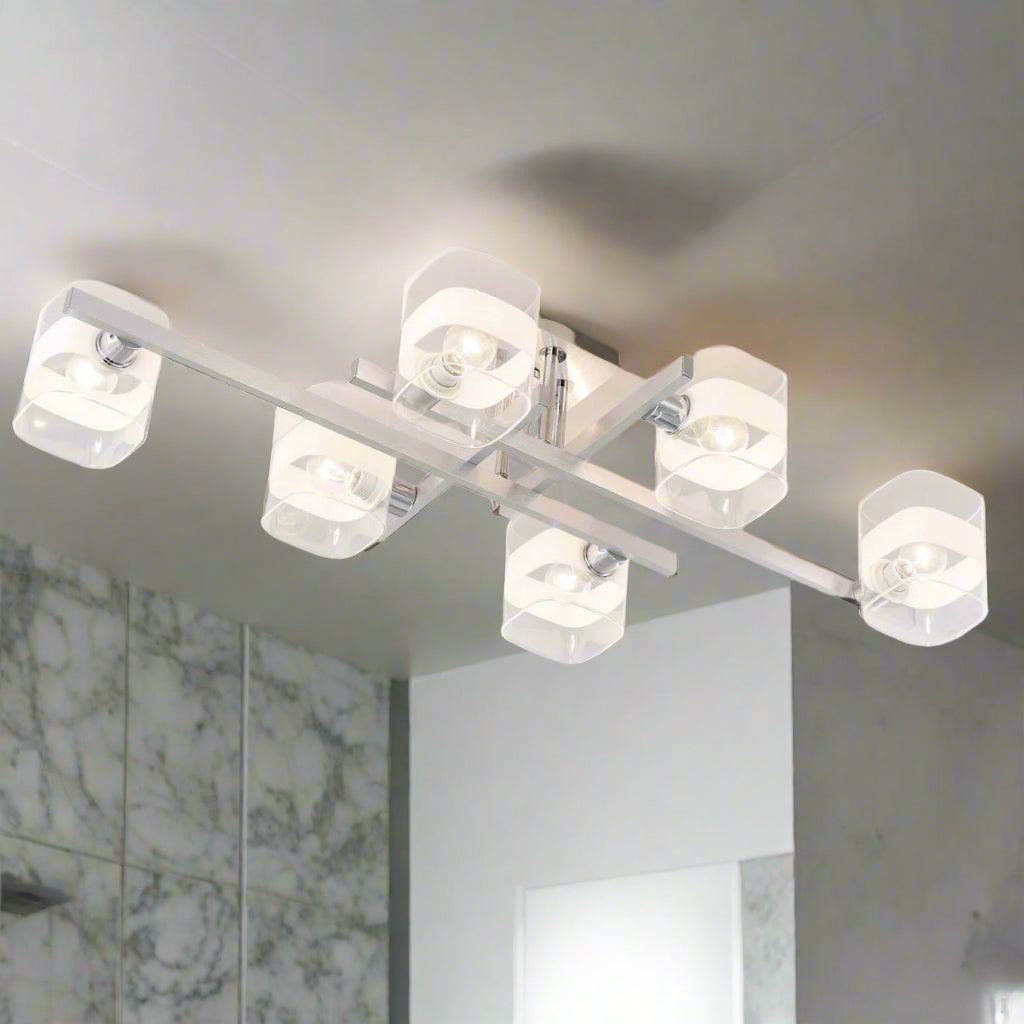 Industrial-style chandelier in brushed metal, with multiple clear and frosted cylindrical glass shades, partially installed with exposed wiring.