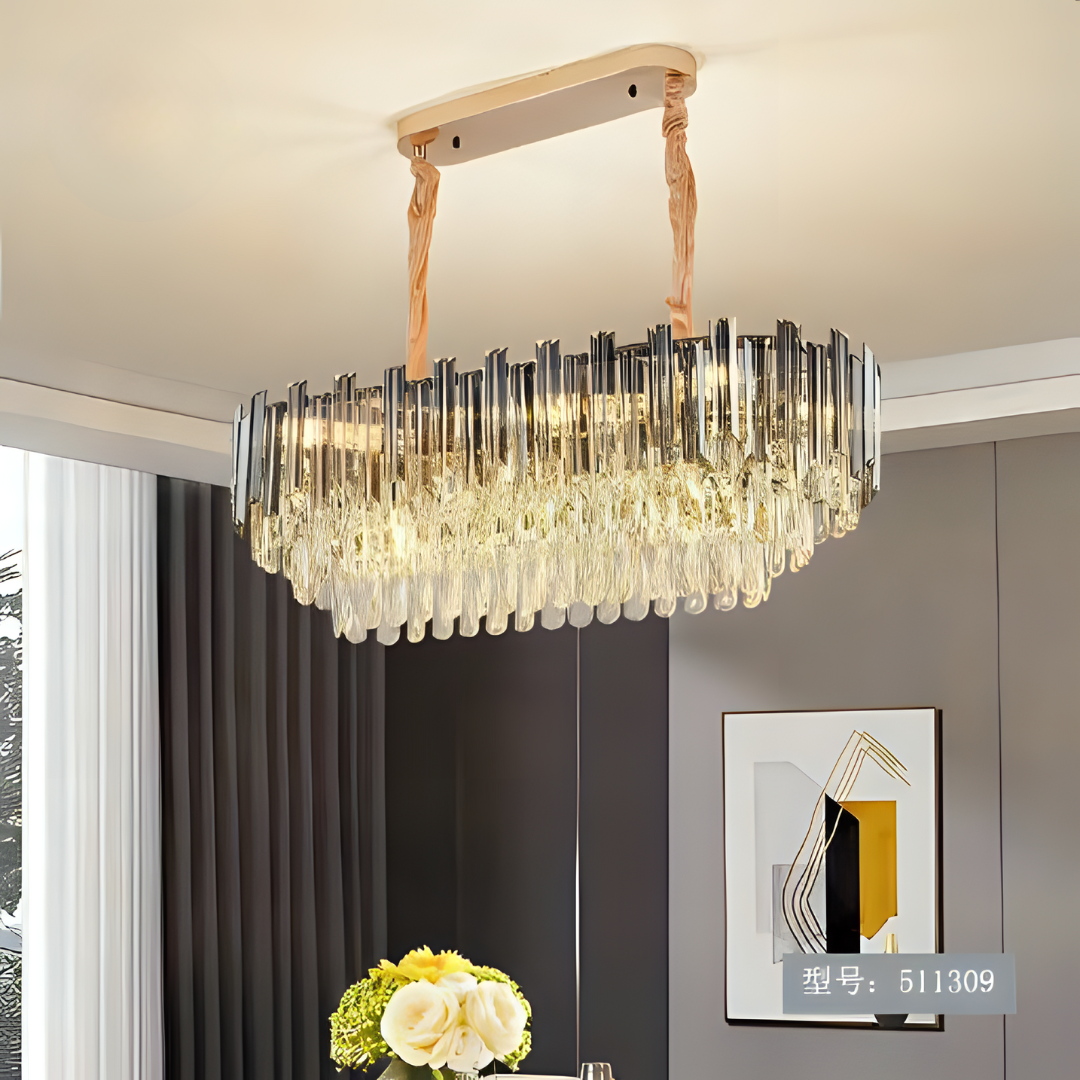 A modern chandelier with gold accents hanging in a well-lit living room with neutral-colored curtains.