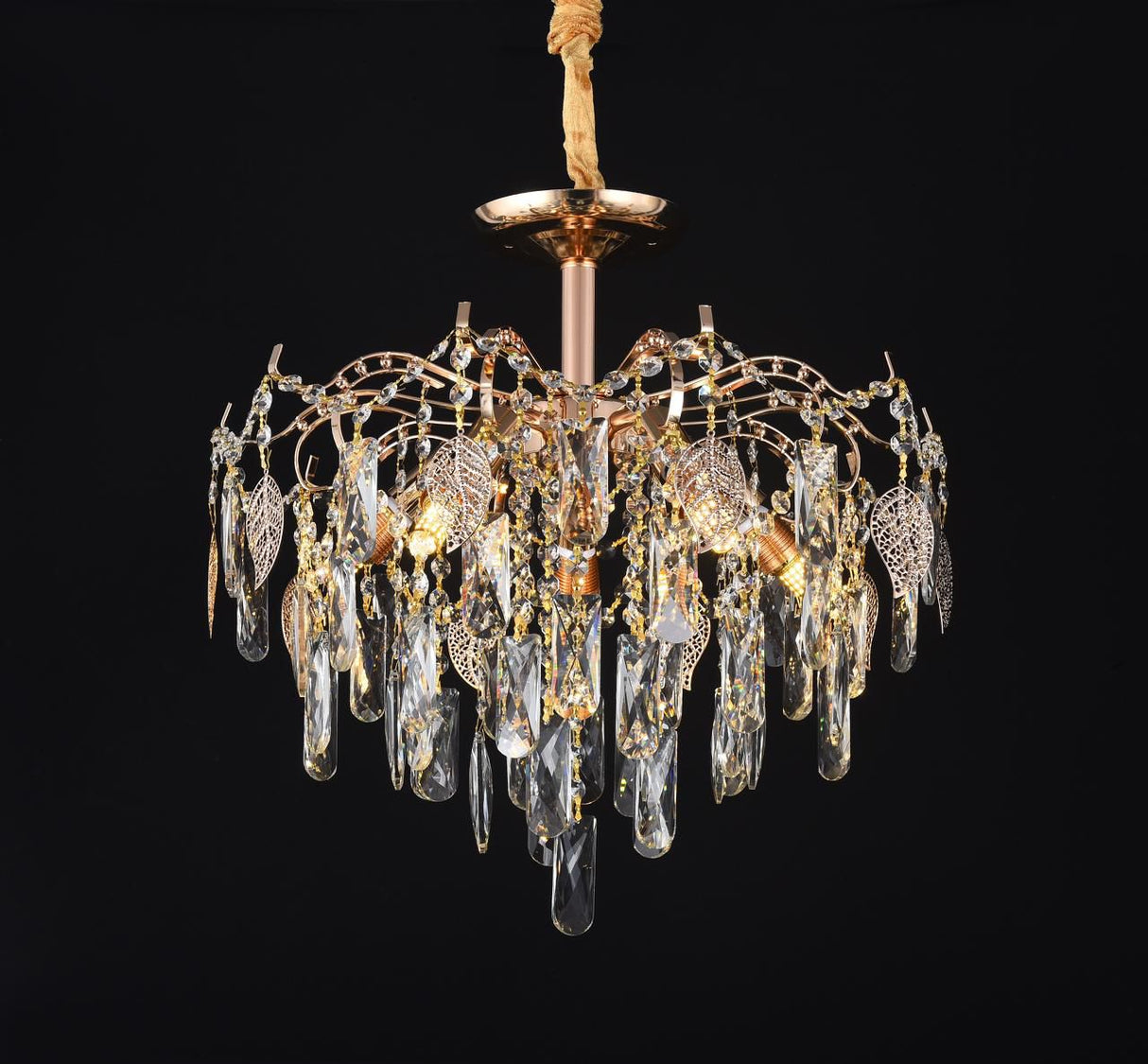 A crystal chandelier featuring a radiant gold finish and a stunning tiered design adorned with shimmering crystal prisms, set against a black background.