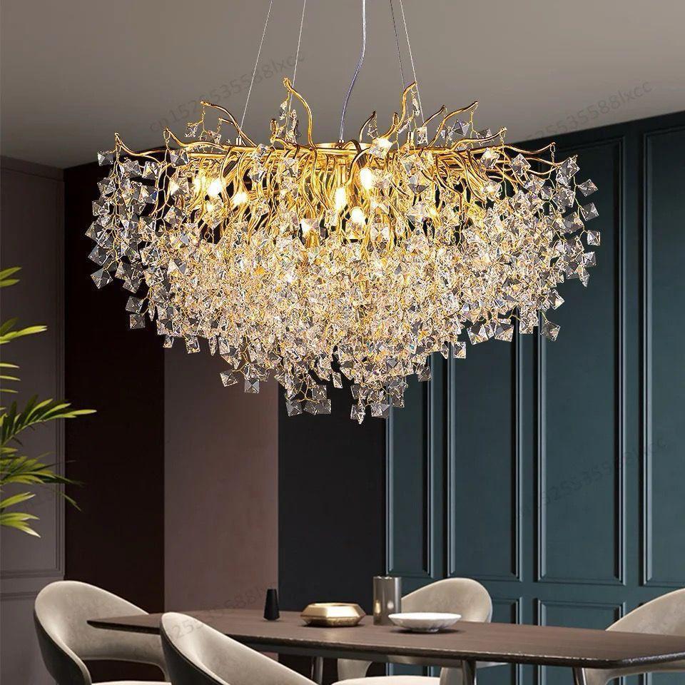 Gold chandelier with crystal branch-like structures suspended above a dining table in a modern dining room.