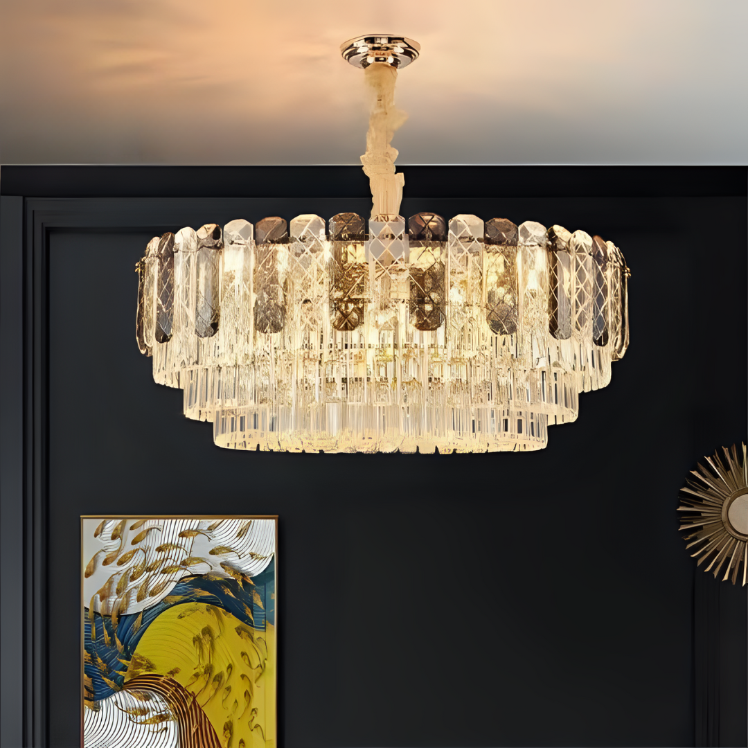 A close-up view of an elegant crystal chandelier with a circular design, mounted on a dark ceiling, with a modern painting in the background.