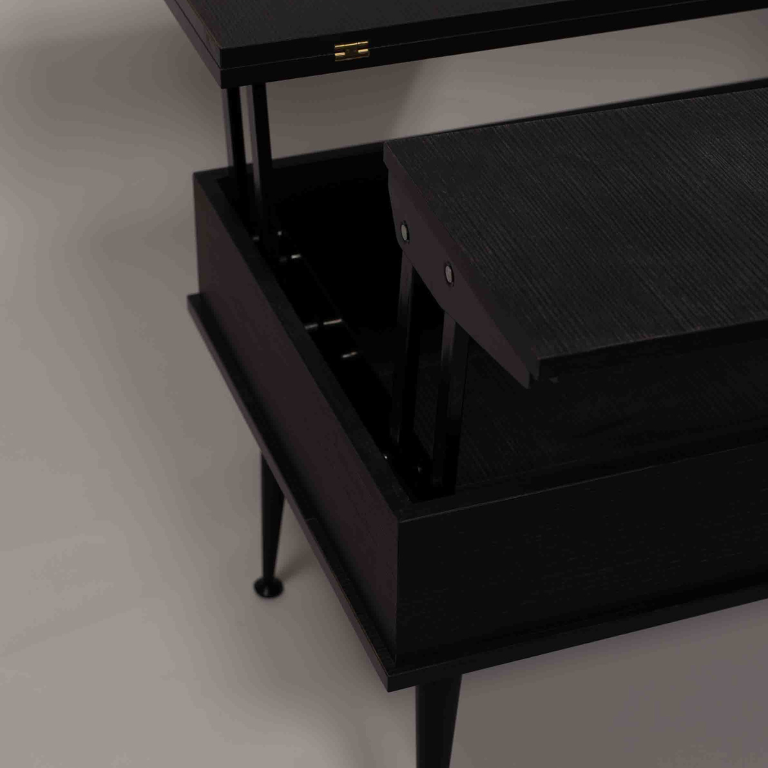 A close-up of a partially open black smart table, showing its internal mechanism, with black metal legs on a white background.