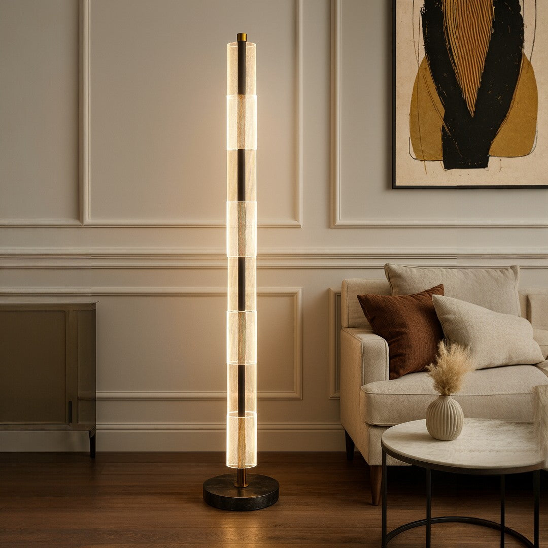 Modern floor lamp in a living room setting with a sofa and abstract art on the wall.