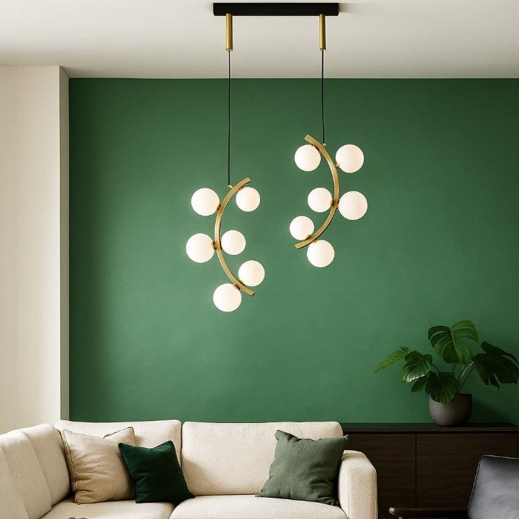 Modern living room with a green wall, white sofa, and decorative lighting fixture.
