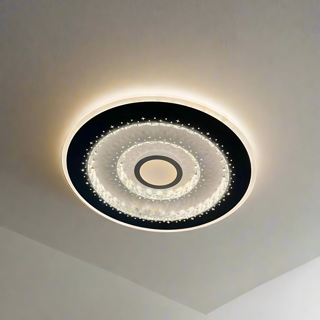 Modern circular flush mount LED ceiling light with concentric rings, crystal-textured accents, and star-like perforations emitting warm white light, mounted on a white ceiling.
