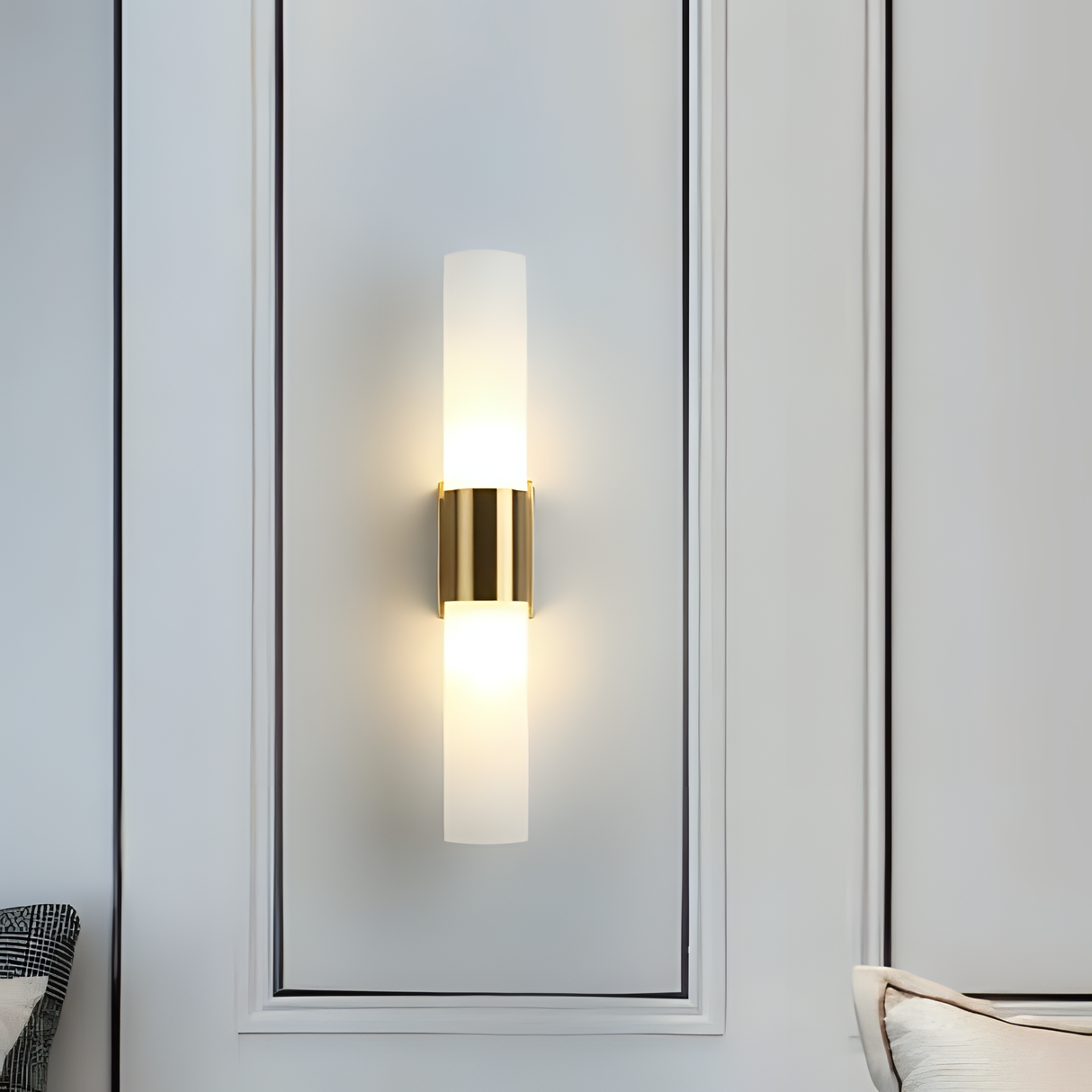 double-cylinder gold and frosted glass wall light, mounted on a white paneled wall.