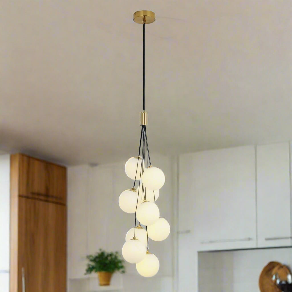 A cluster of frosted white glass globes hanging from a gold fixture, forming a cascading pendant light design.