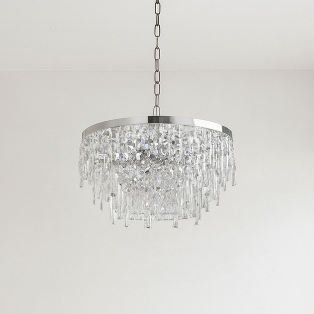 Modern living room with a gray sectional sofa, round glass coffee table, and crystal chandelier.