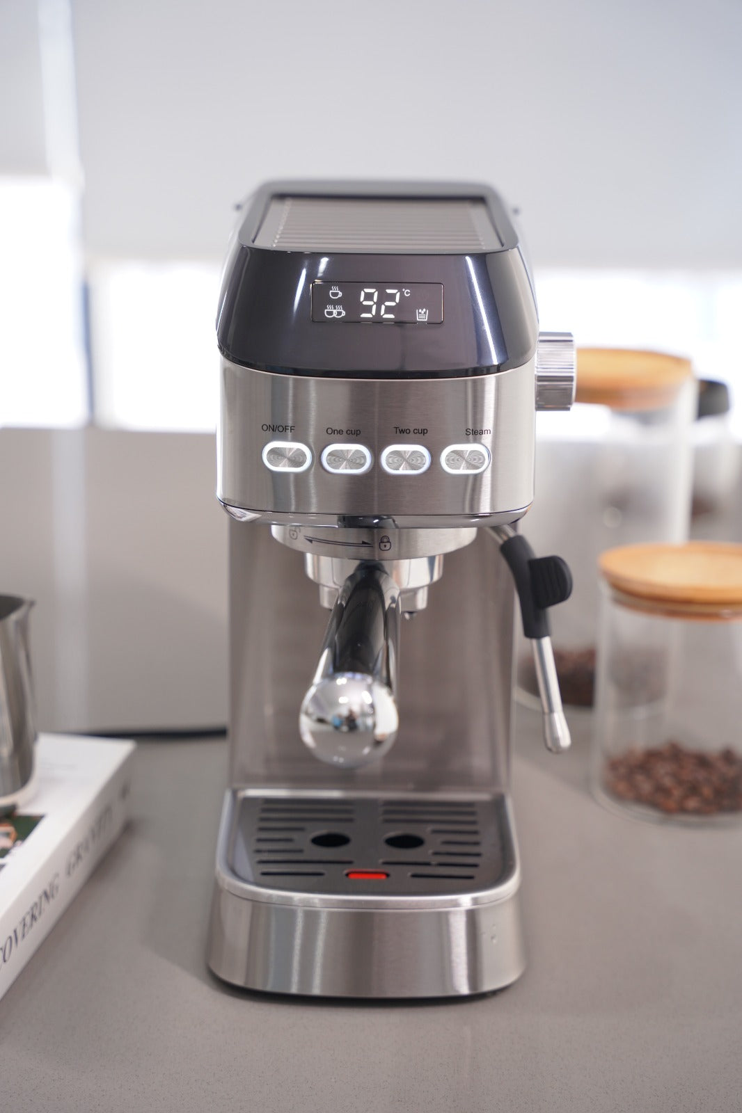 Stainless steel espresso machine on a kitchen counter with coffee beans in the background.