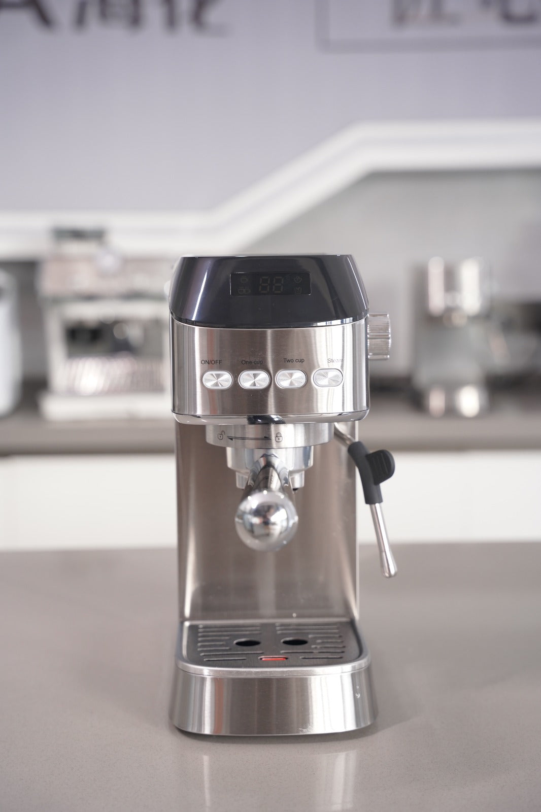 Stainless steel espresso machine on a reflective surface with blurred background