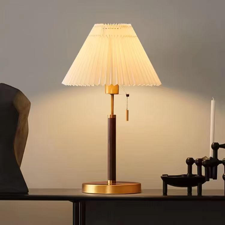 Table lamp with pleated shade on a wooden table against a neutral background