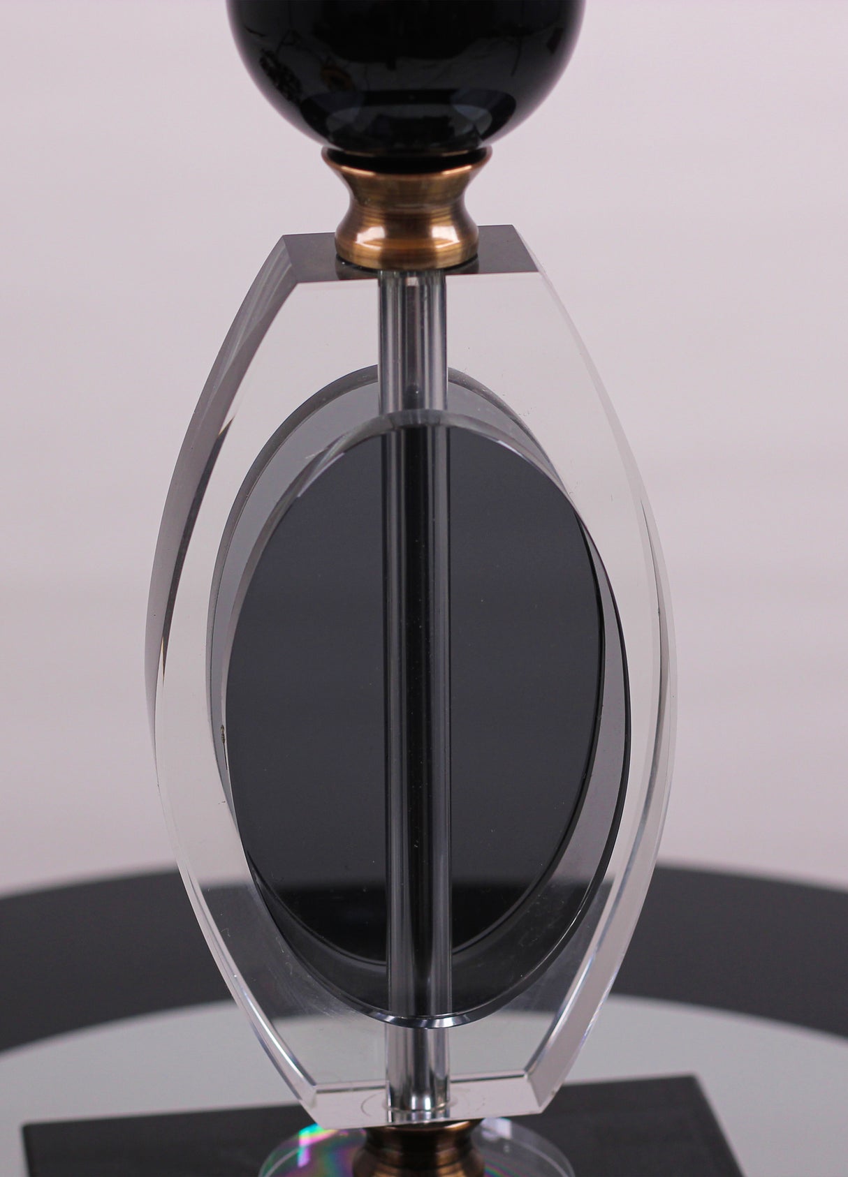 base is crafted from a combination of gold metal and transparent black glass with a geometric design.