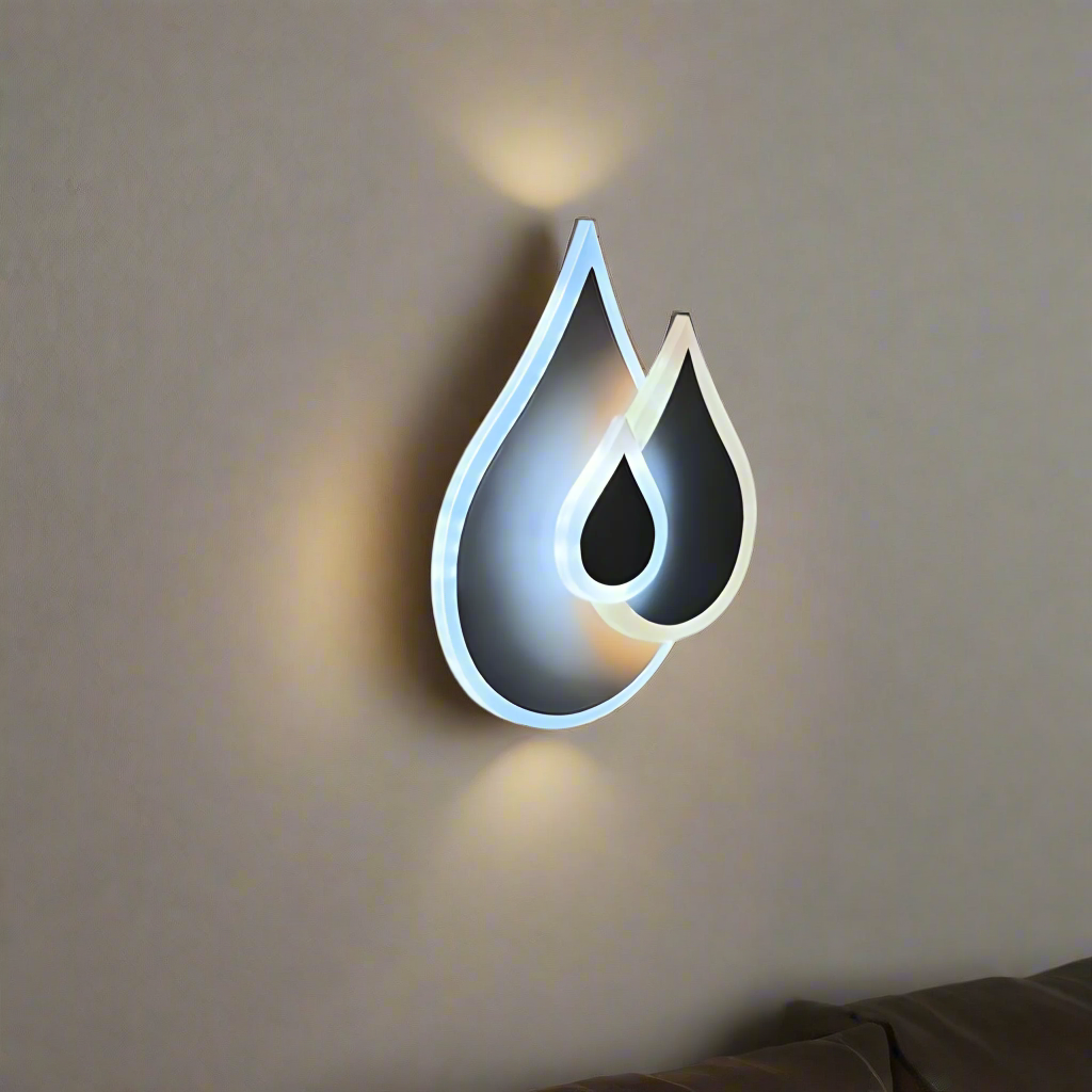 Wall-mounted LED light fixture shaped like two overlapping water droplets, with a soft white and warm white glow illuminating the surrounding wall.