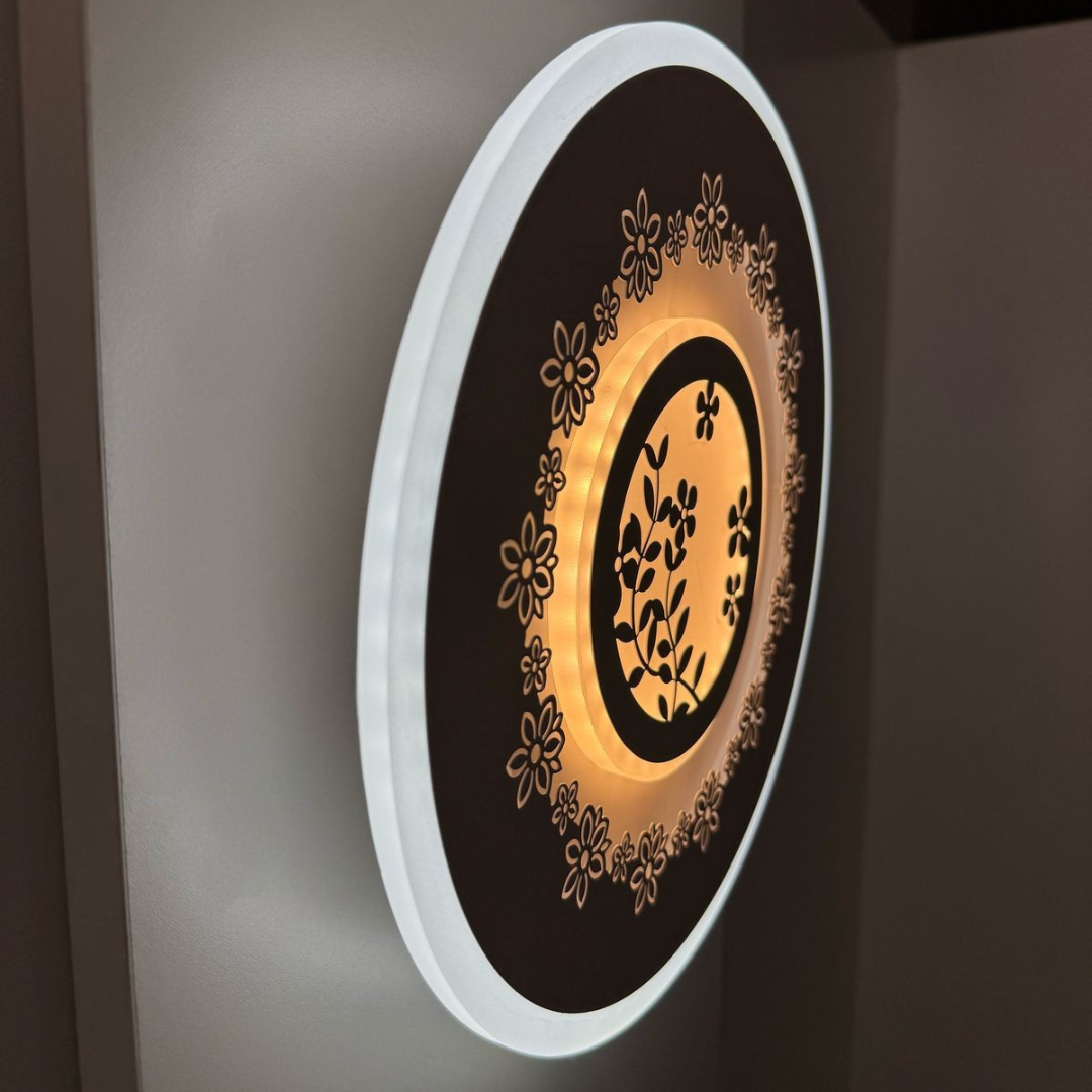 White round wall lamp featuring a small flower motif, mounted on a white wall.