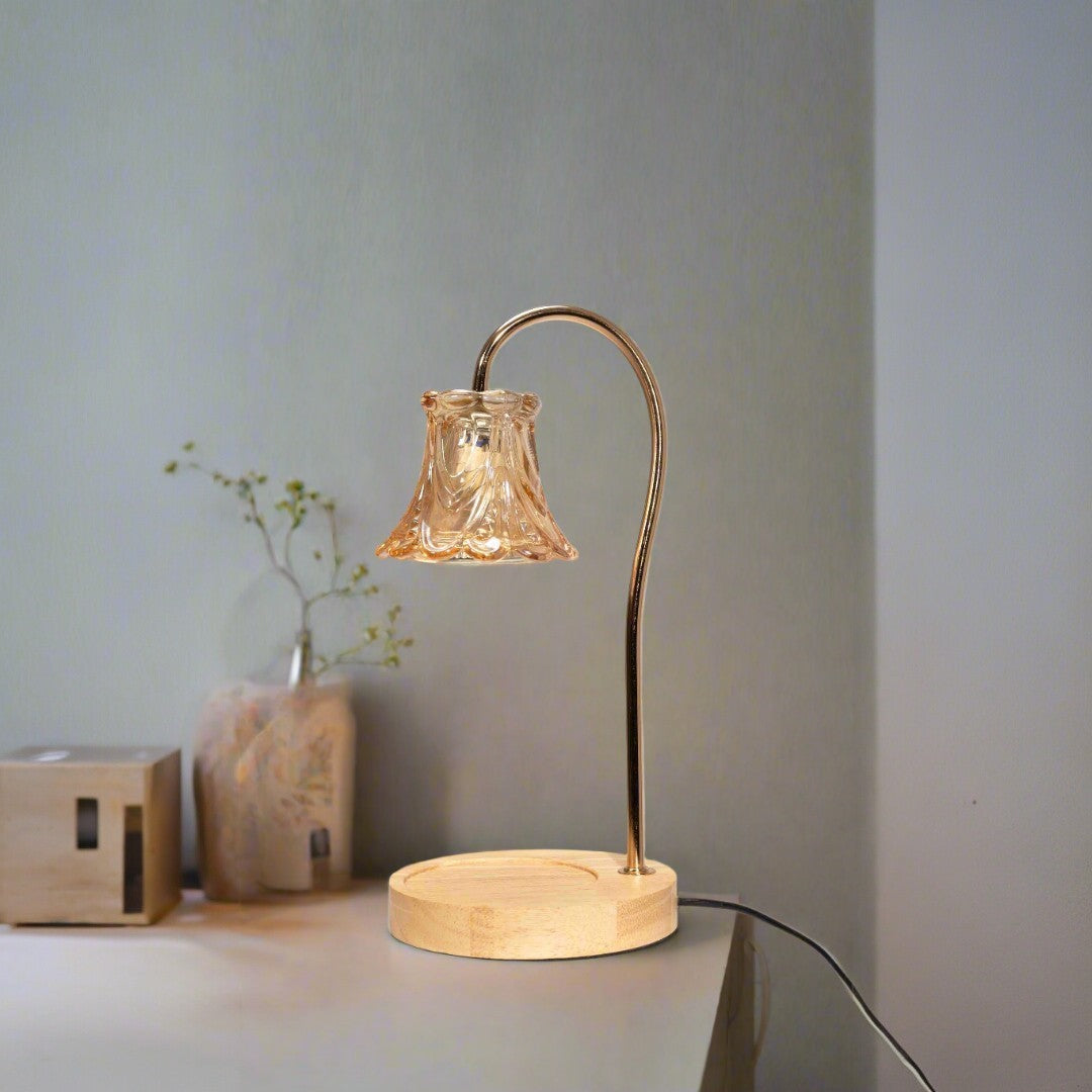 A vintage-inspired table lamp with a curved bronze arm holding a delicate bell-shaped glass shade, sitting on a round wooden base. Placed on a round white table.