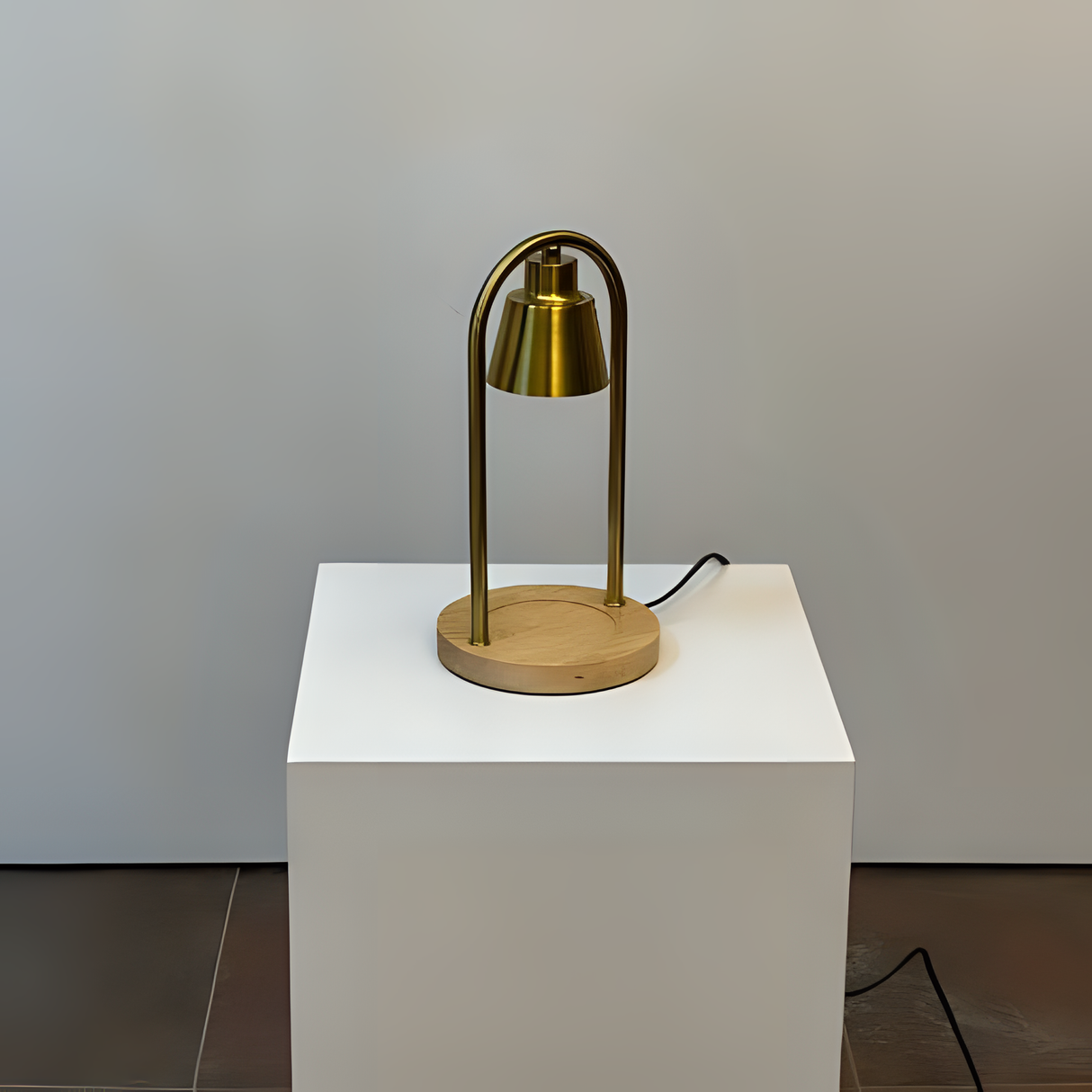A sleek table lamp featuring a metallic arched handle, positioned on a white pedestal