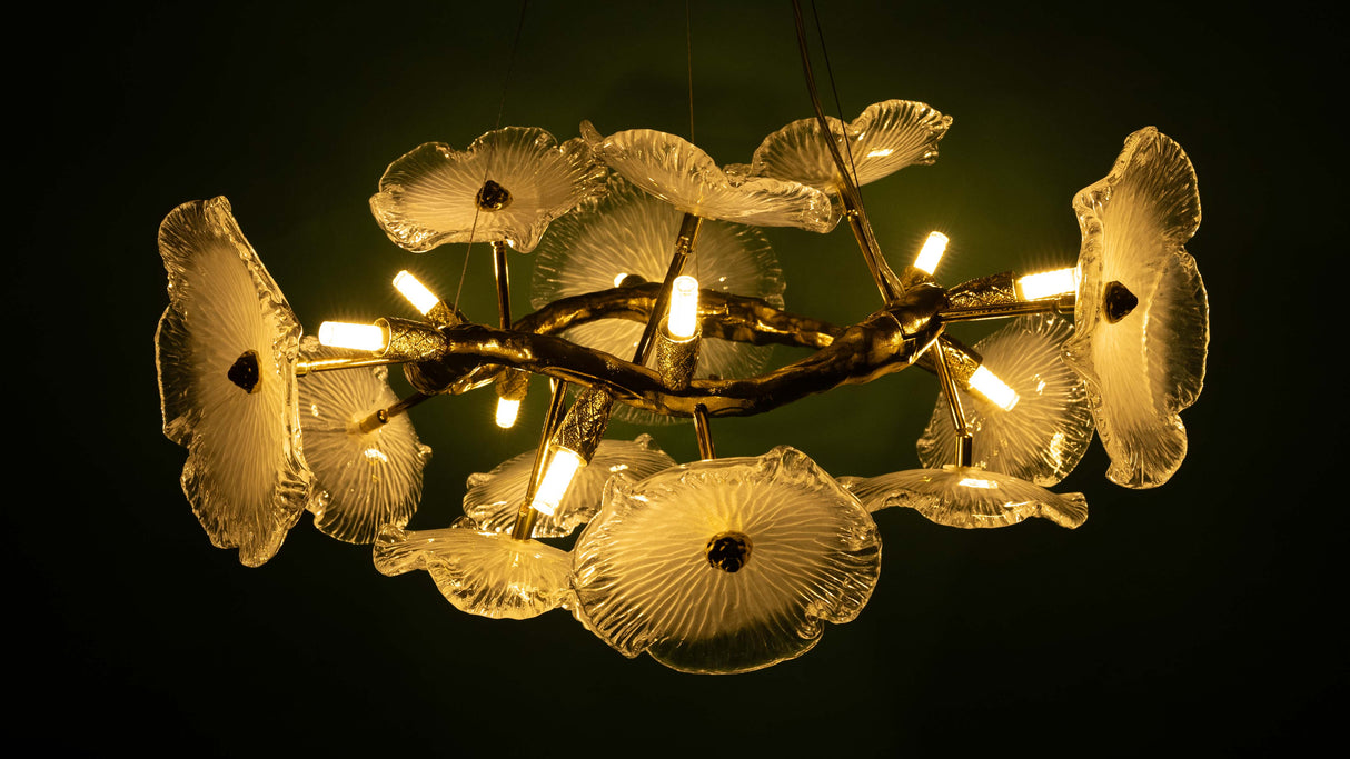 A nature-inspired chandelier with golden branches and glass flower-shaped lampshades, illuminated with warm lighting.