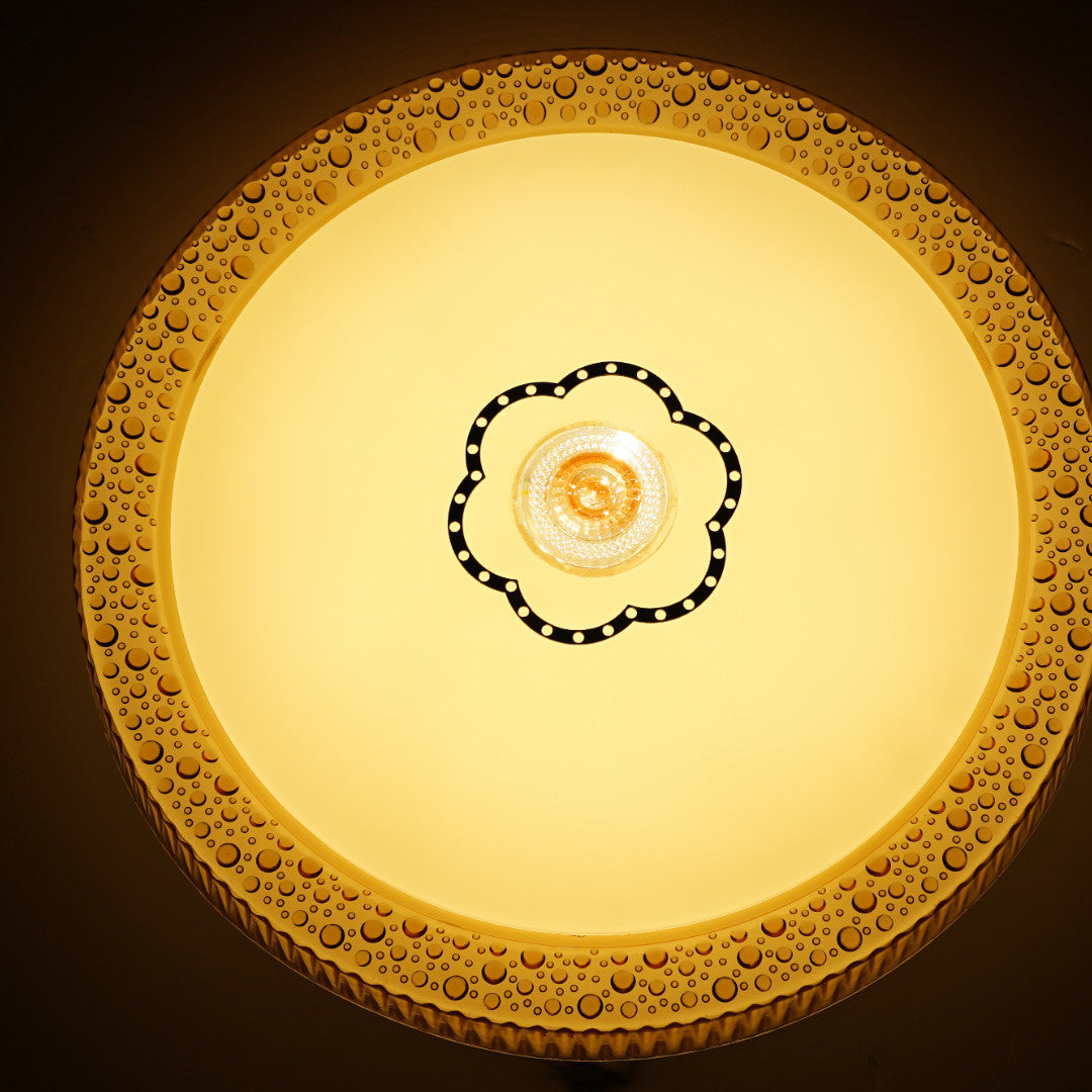 A circular close-to-ceiling LED light in warm white. The frame is decorated with an intricate gold floral pattern, and a black-edged flower motif at the center encircles the LED core. Ideal for hallways or bedrooms with classic interiors.