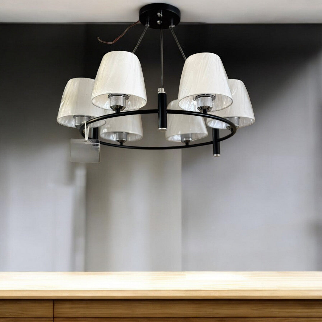 A black chandelier with a circular frame and white fabric lampshades, mounted on a ceiling.