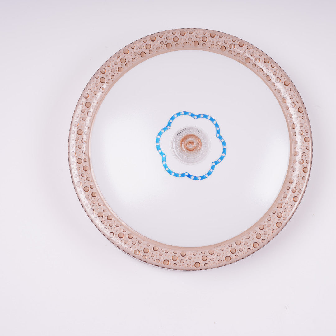 a rose gold circular flush mount ceiling light featuring an ornate ring and a central blue-edged flower motif around the LED. Best for elegant indoor areas like lounges or bedrooms.