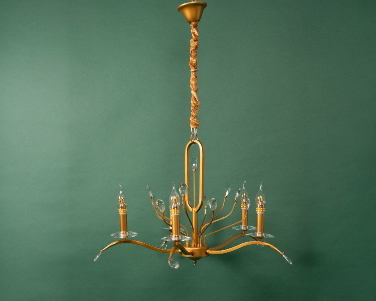 A vintage-inspired gold chandelier with delicate curved arms and candle-style bulbs, hanging against a green background.