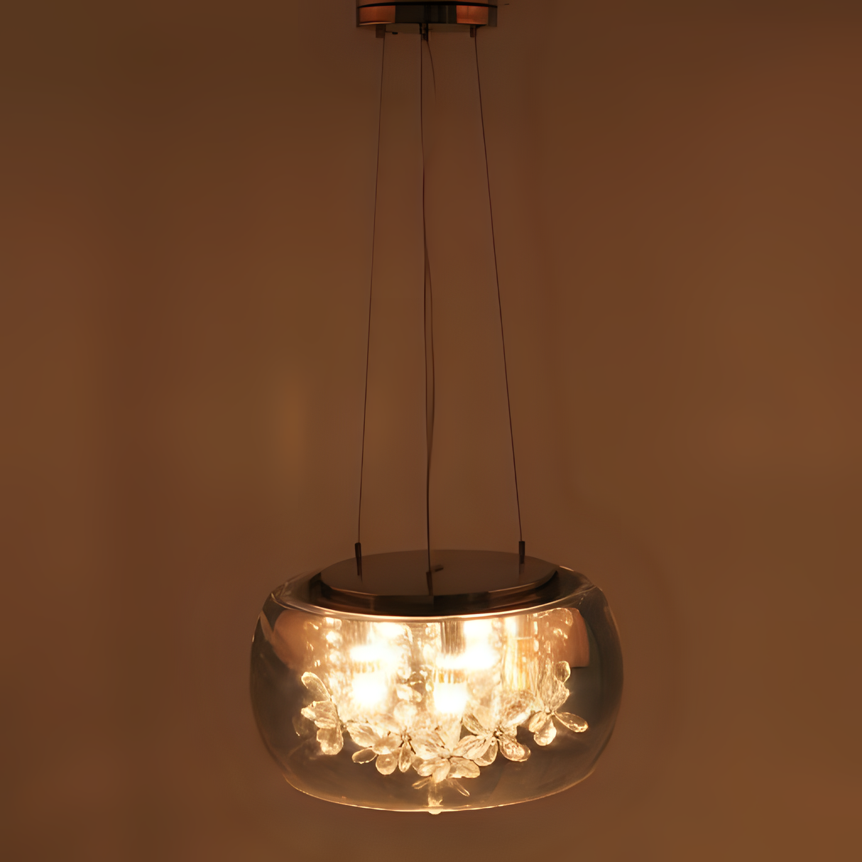 A contemporary acrylic pendant chandelier with a rounded transparent dome shade, featuring hanging crystal droplets inside, suspended by thin wires from the ceiling.