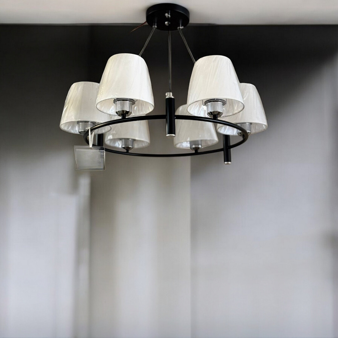 A black chandelier with a circular frame and white fabric lampshades, mounted on a ceiling.