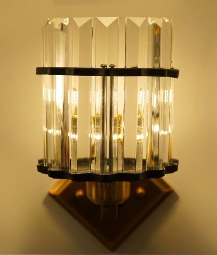 A modern gold and crystal wall sconce with vertical glass rods and a gold metal mounting plate.