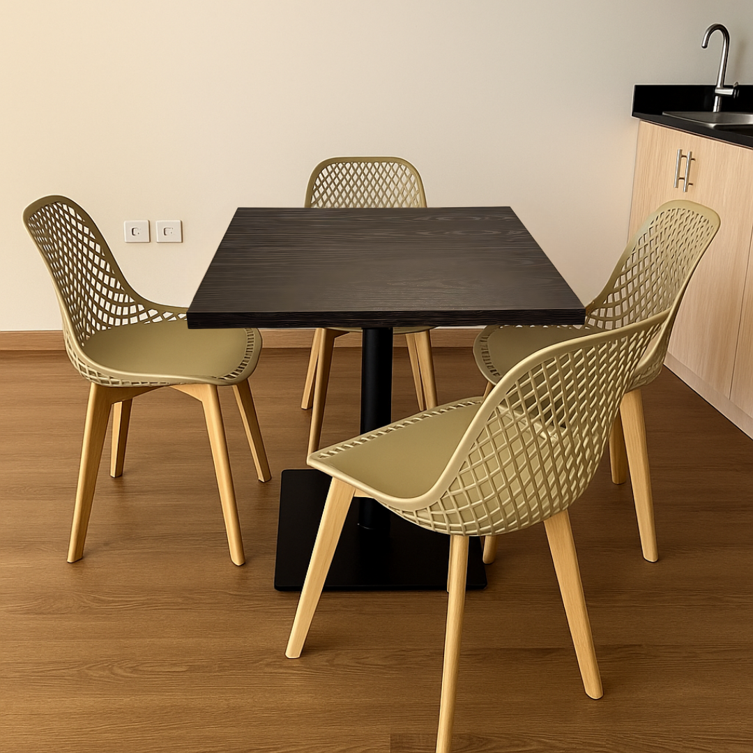 Square brown table with four green chairs in a room with wooden flooring and beige walls.