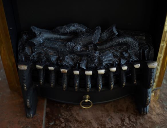 A close-up of realistic artificial logs with a blackened, charred appearance inside an electric fireplace.