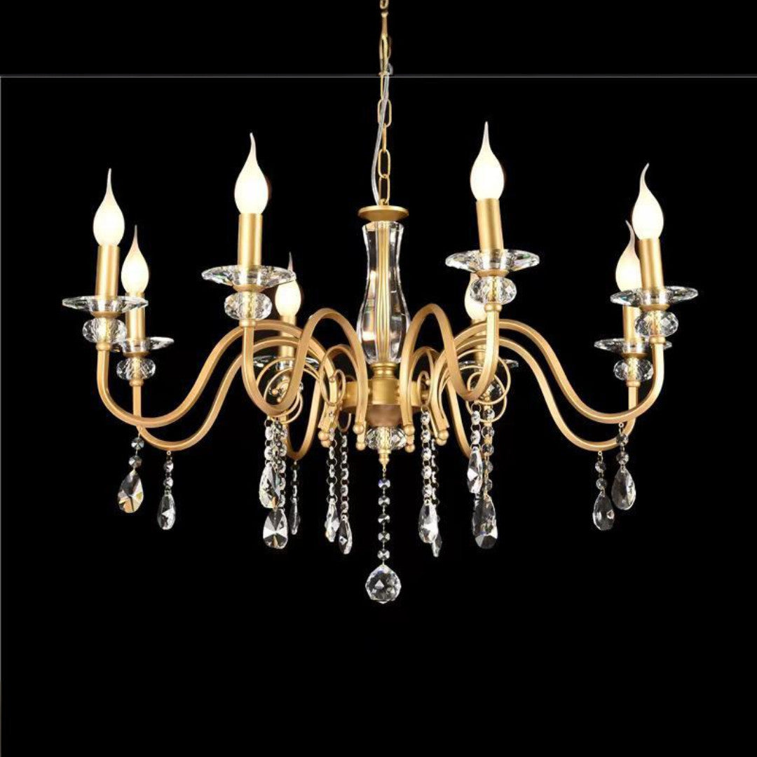 A gold chandelier with curved arms, crystal accents, and candle-shaped bulbs, set against a black background.