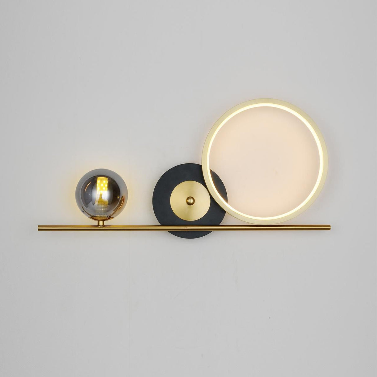 – A sleek gold fixture featuring a circular LED ring, a black disc, and a small smoked glass globe equipped with a led lamp G9, mounted on a slim horizontal bar.