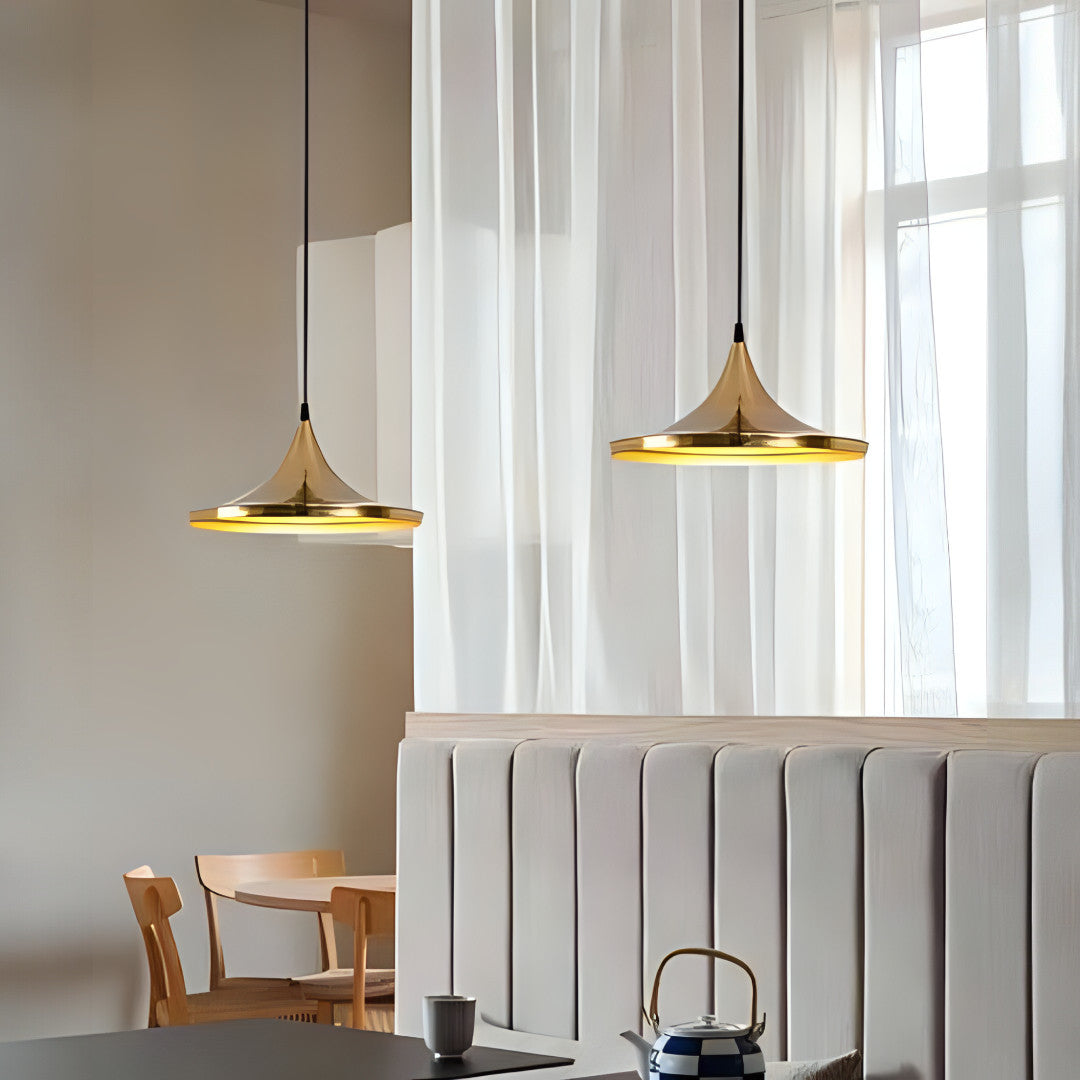 Two gold pendant lights with wide, flared shades hanging over a cozy dining area.