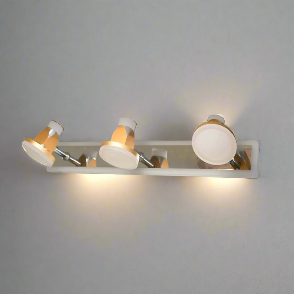 A contemporary three-light wall fixture with a polished metal base, featuring white and gold adjustable lampshades shaped like small spotlights.