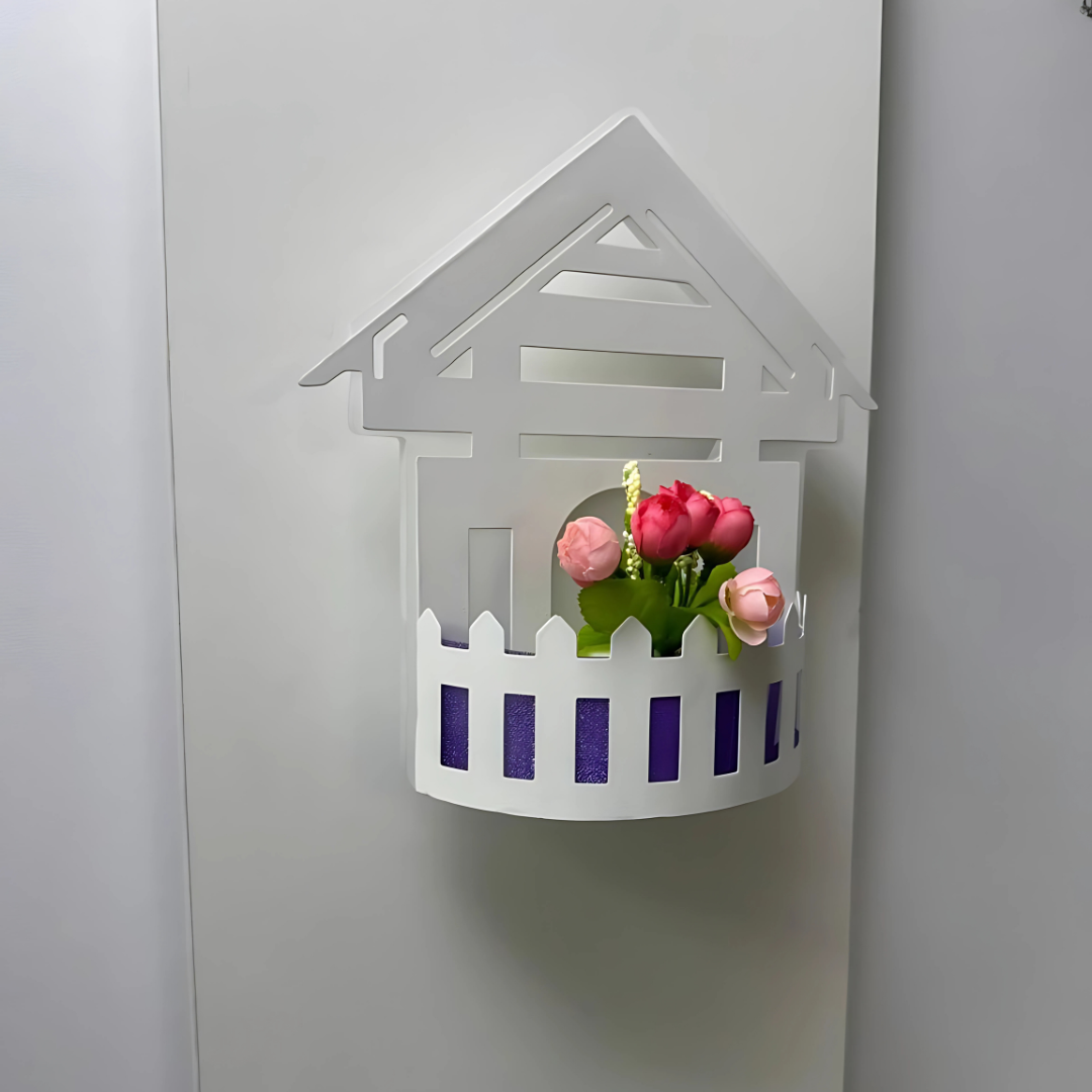 Wall-mounted LED light fixture designed in the shape of a white house , featuring a cork-style built-in compartment holding artificial pink and red tulip flowers.