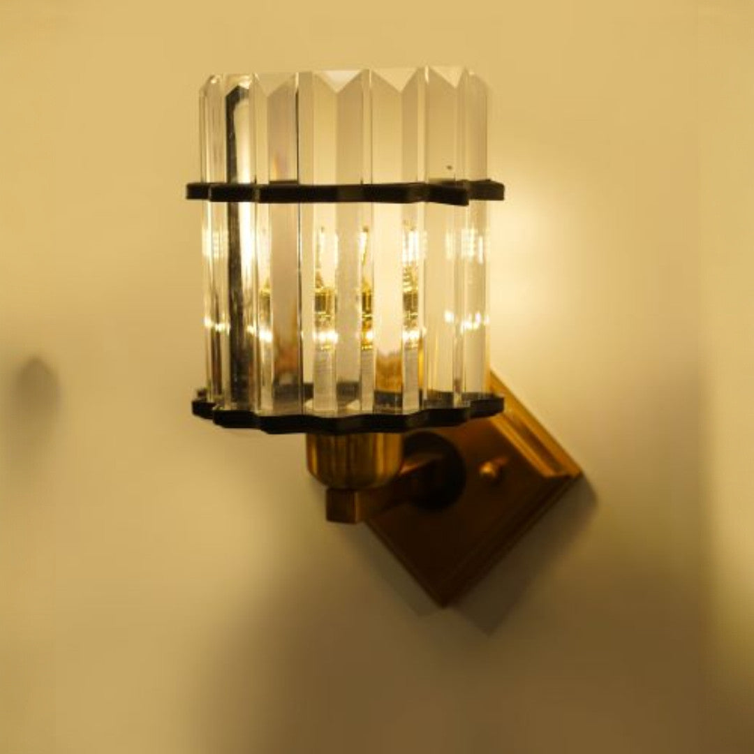 A refined wall light with an angular arrangement of clear glass rods attached to a gold base. The symmetry of the glass rods creates a sophisticated lighting effect with a led lamp E27.