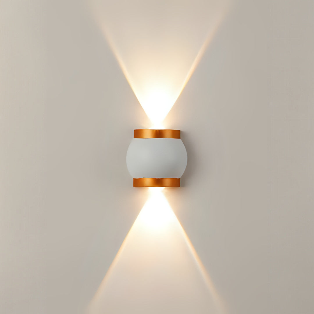 A compact cylindrical wall sconce with gold and white detailing, casting light both upwards and downwards.