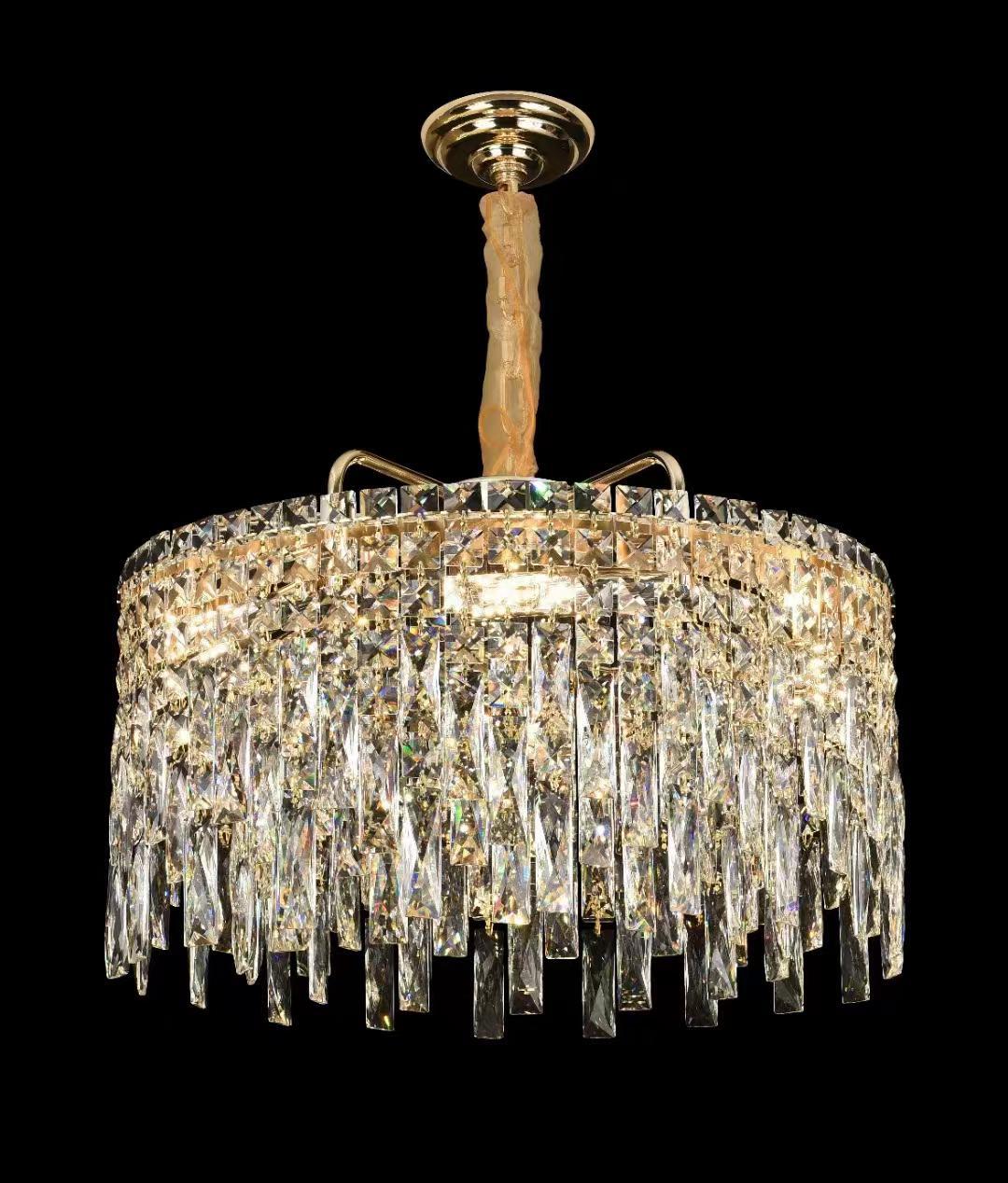 A grand crystal chandelier with cascading glass elements, shining brilliantly against a black background.