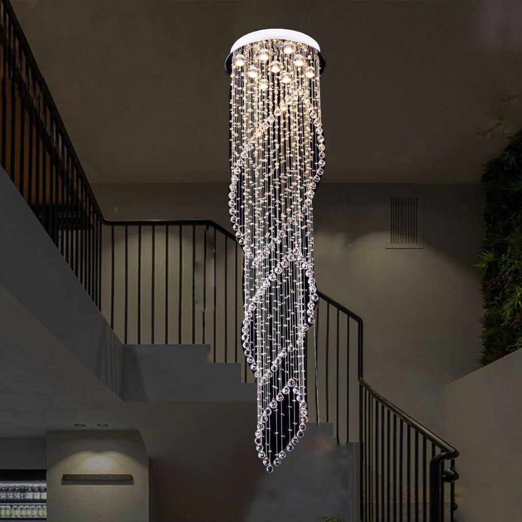 Tall spiral crystal chandelier in chrome finish hanging from a double-height ceiling in a staircase foyer.
