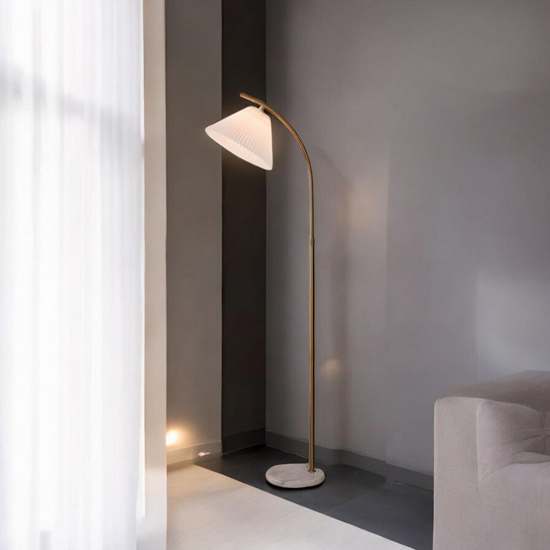 A sleek arched floor lamp with a white lampshade, positioned in a minimalist interior beside a white sofa.