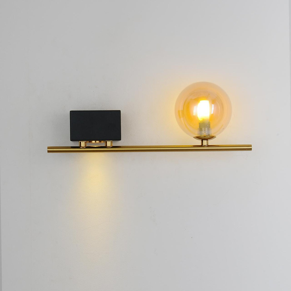 wall light have A sleek gold bar with a cylindrical black box on one side, housing an LED light, and an exposed bulb on the other