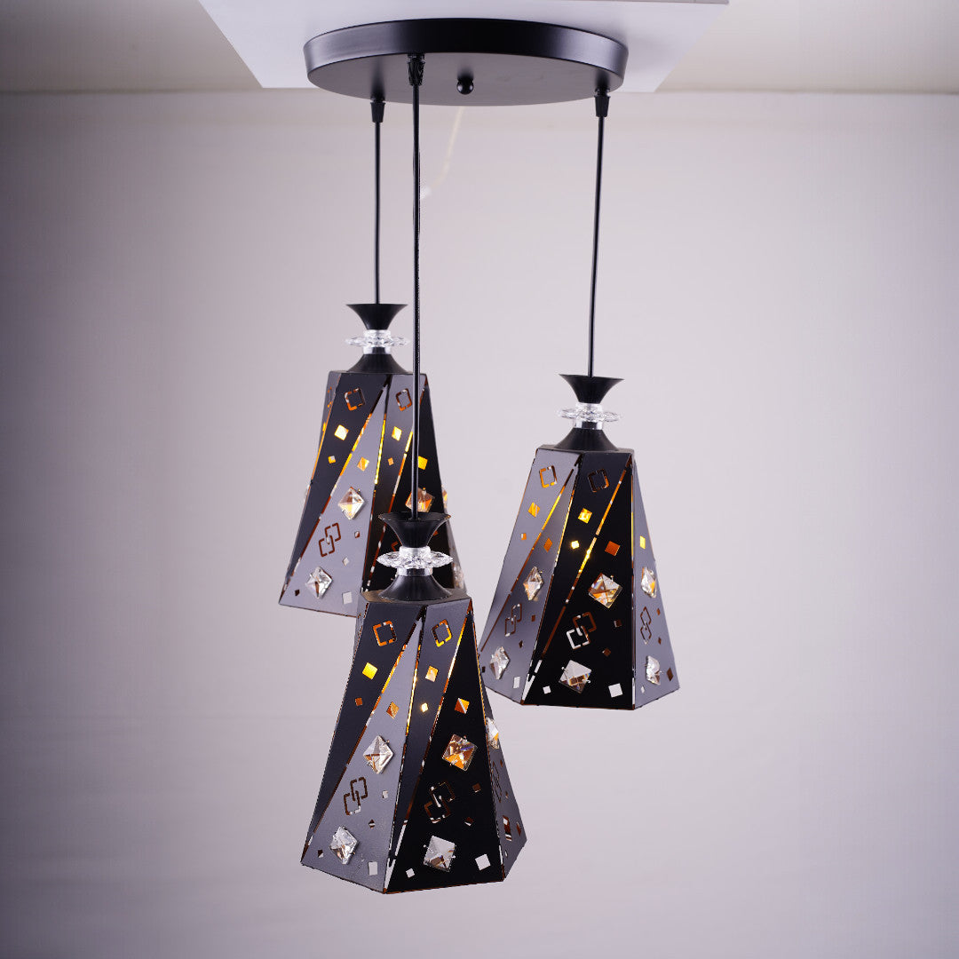 A cluster of three black and gold angular pendant lights with intricate patterns, suspended from a single ceiling mount.