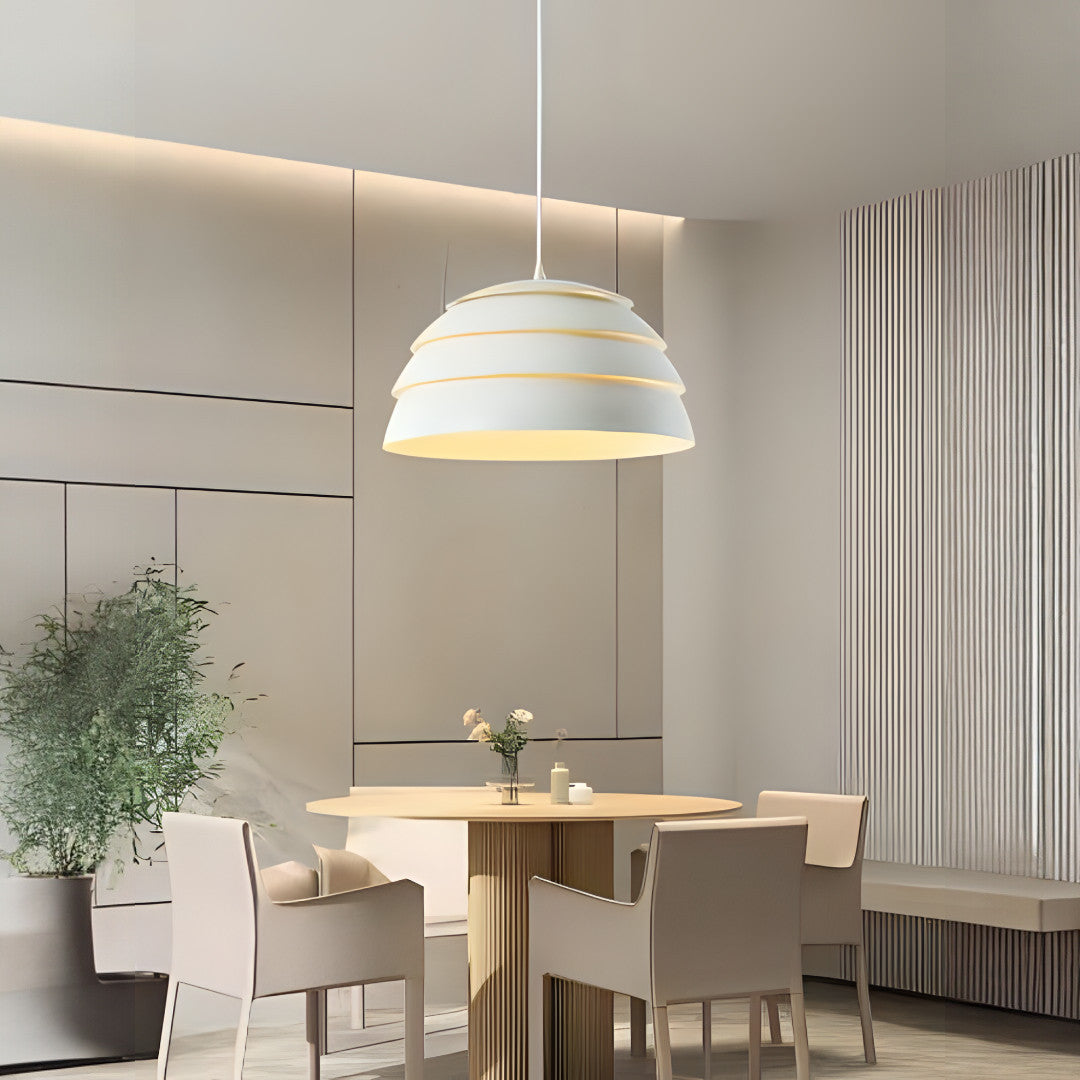 A minimalist white dome-shaped pendant light hanging above a dining table in a modern dining room.