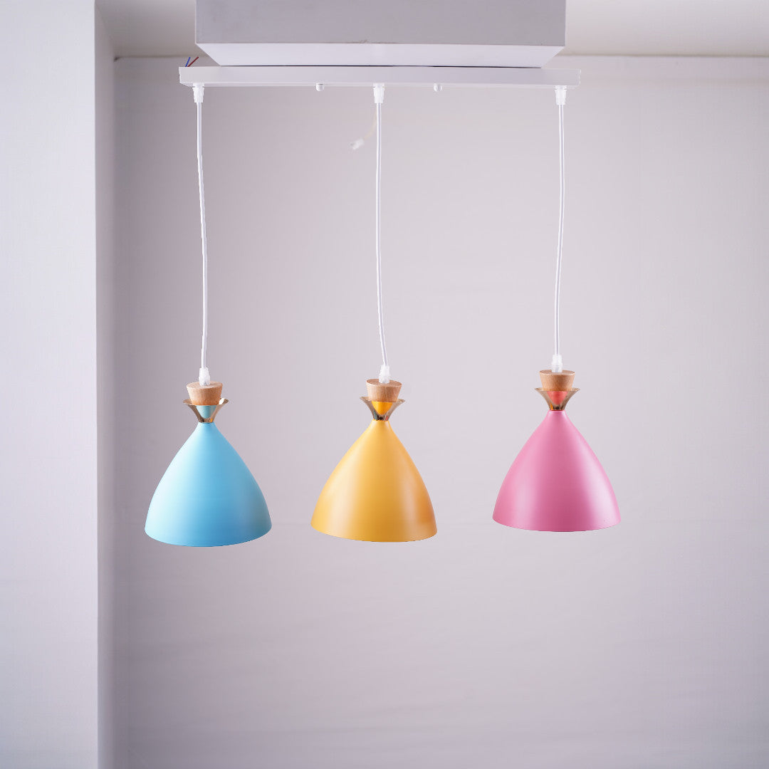 A set of three colorful pendant lights in pastel blue, gold, and pink, each with a conical shape, hanging from white cords.