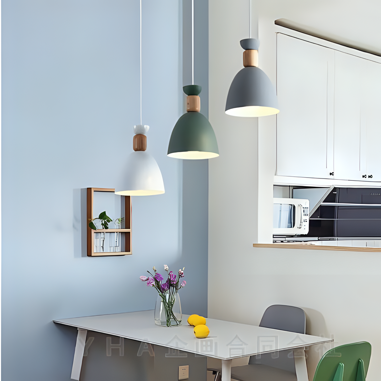 A close-up of three pendant lights in green, white, and copper colors hanging above a small dining area with a vase of flowers on the table.