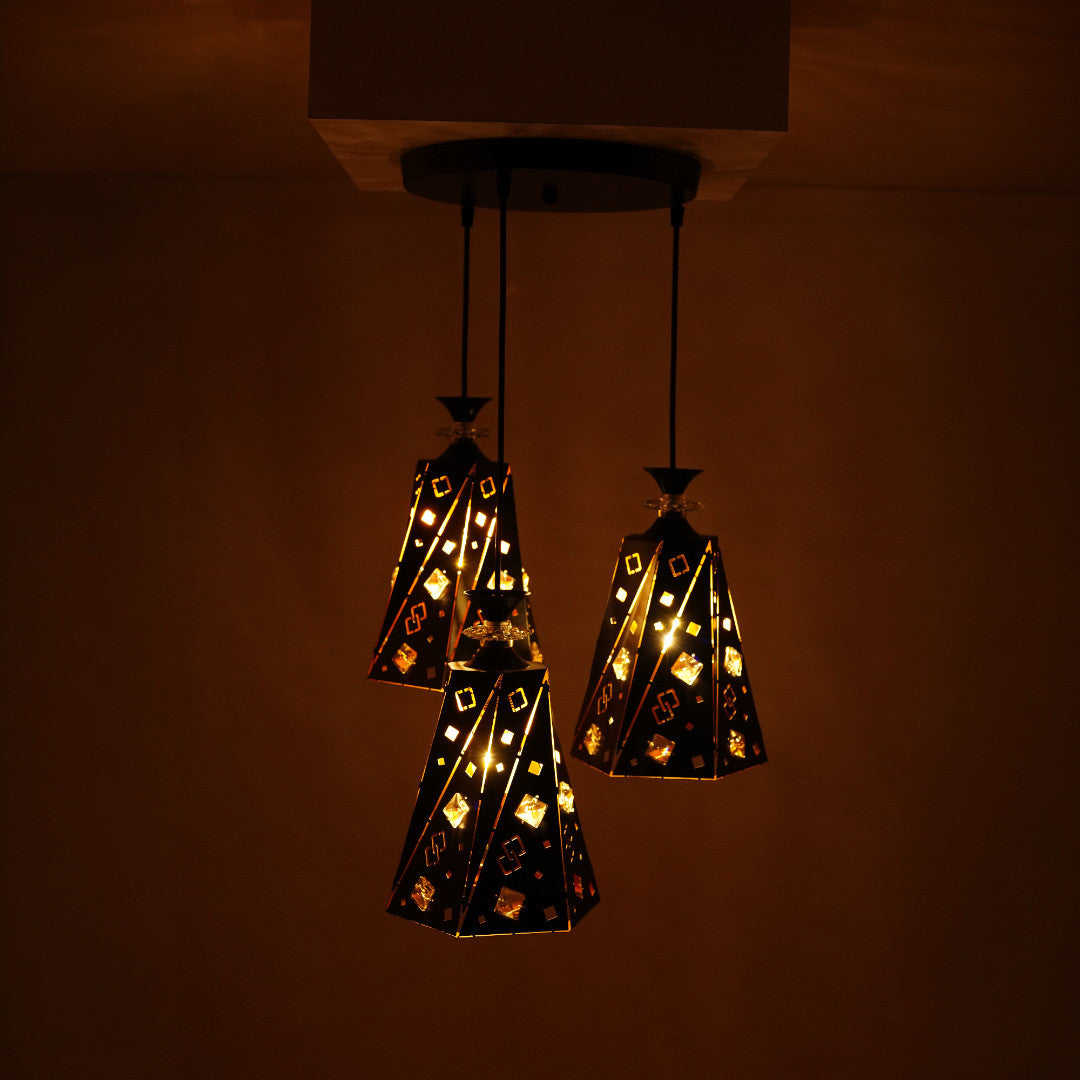 The black and gold pendant light cluster, glowing warmly in a dimly lit room.