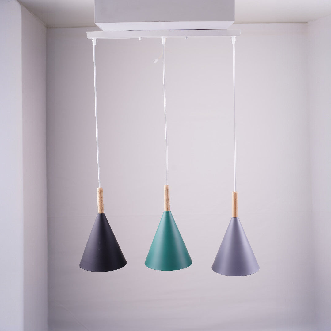 A modern pendant light fixture with three cone-shaped lampshades in black, green, and grey, hanging from a white rectangular ceiling mount.