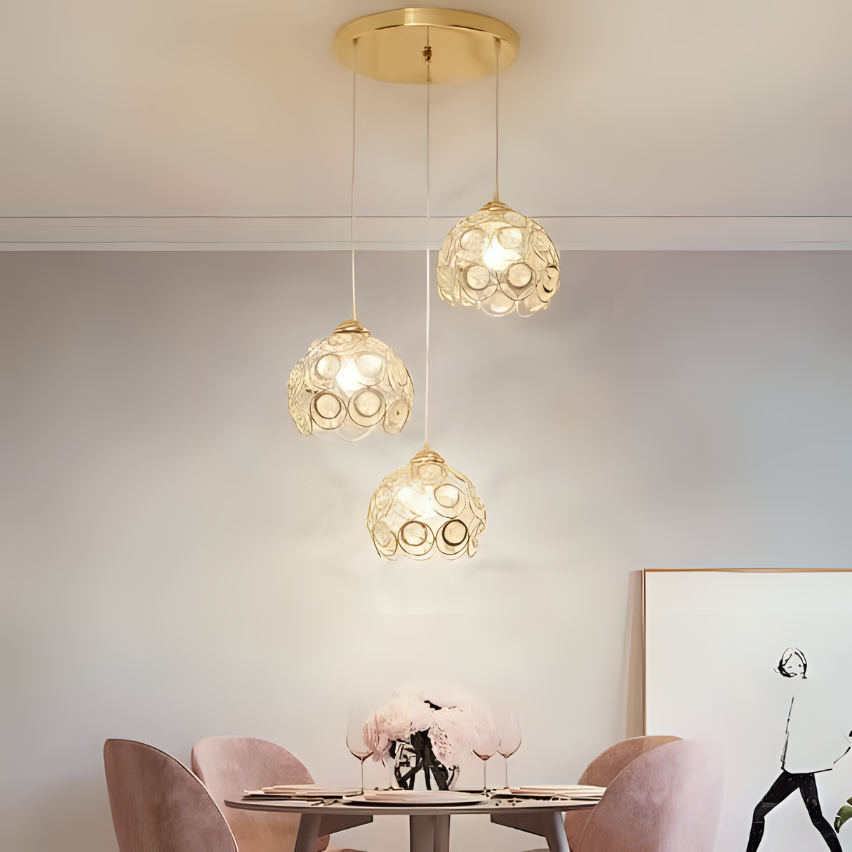 Three gold metal pendant lights, suspended at different heights, adding a glamorous and warm glow to a dining space.